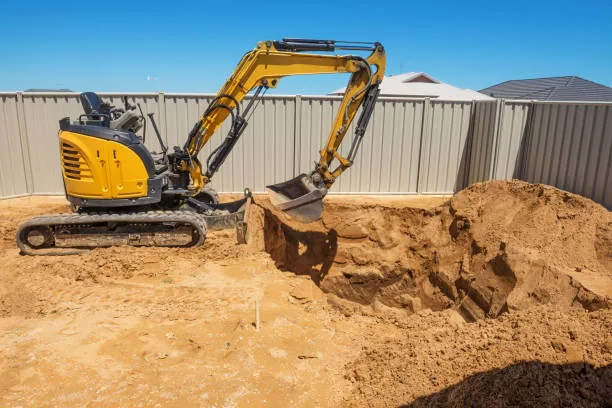 Mini excavator digging pool or pond excavation in backyard